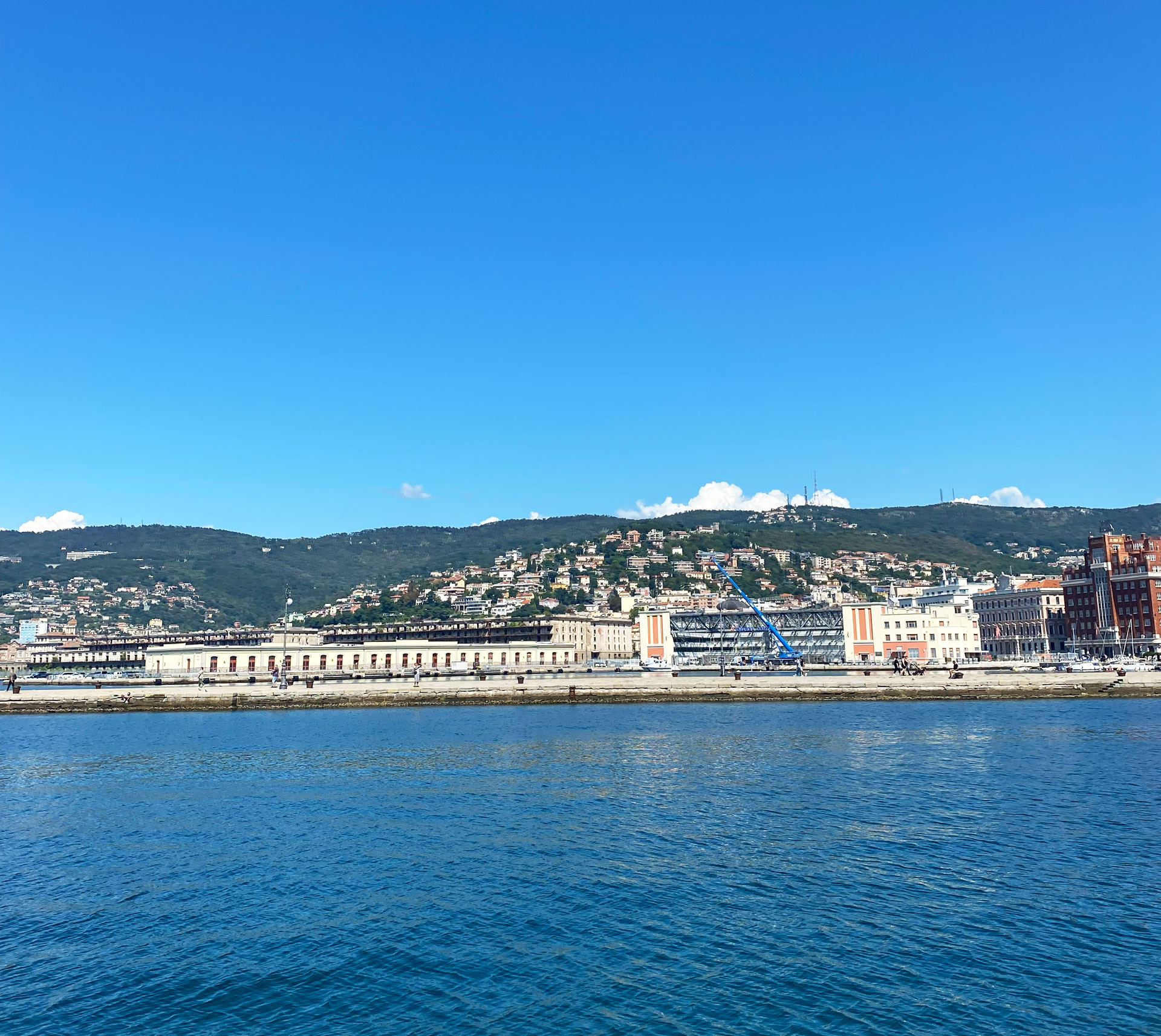 Blick vom Wasser auf Hafen und Stadt Triest.